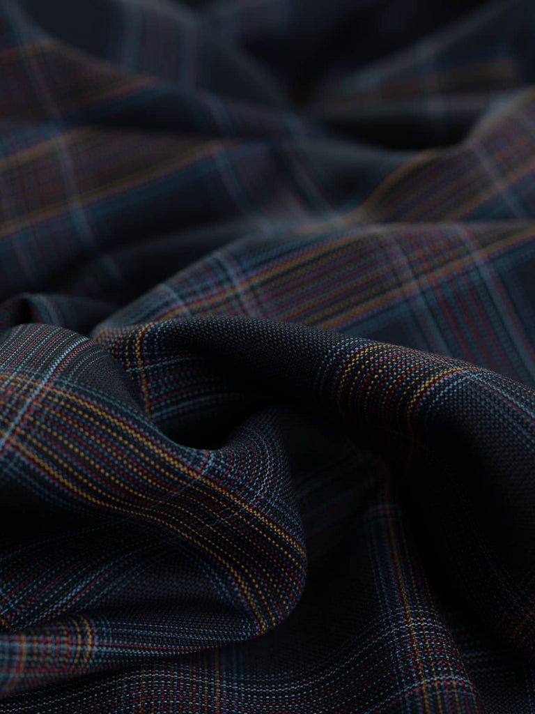 Midnight Spectrum Check is a luxurious 100% wool superfine worsted suiting fabric, featuring a classic darkest midnight navy base with a subtle multi-lined windowpane check in sky blue, gold, red, and French navy. This light, Italian-woven fabric has a soft, chic drape and is perfect for creating timeless jackets, trousers, skirts, and bias-cut dresses.