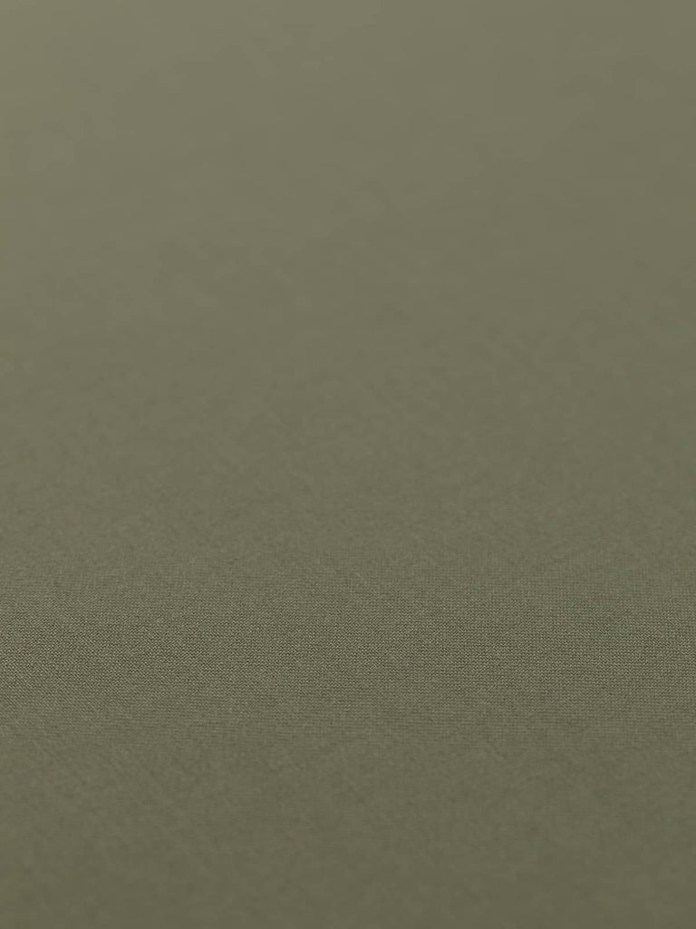 Flat, angled view of the Dusted Olive wool-blend fabric laid out to show its solid, fine twill weave and calm, olive-toned green-beige shade. The closely woven surface and understated color make it ideal for both tailoring and structured accessories