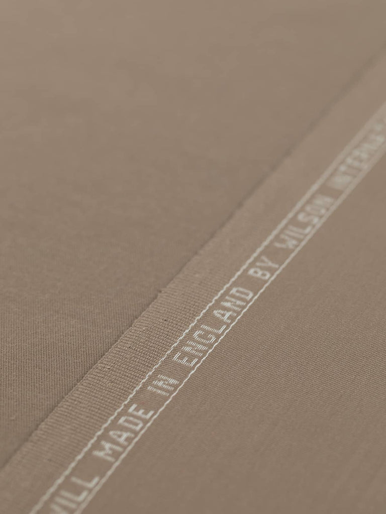 Flat, angled view of Desert Sand fabric laid out to showcase the even, fine twill weave and silky texture. The warm sand beige color, with faint grey undertones, makes it ideal for tailored garments or smart accessories with a minimalist, military-inspired edge.