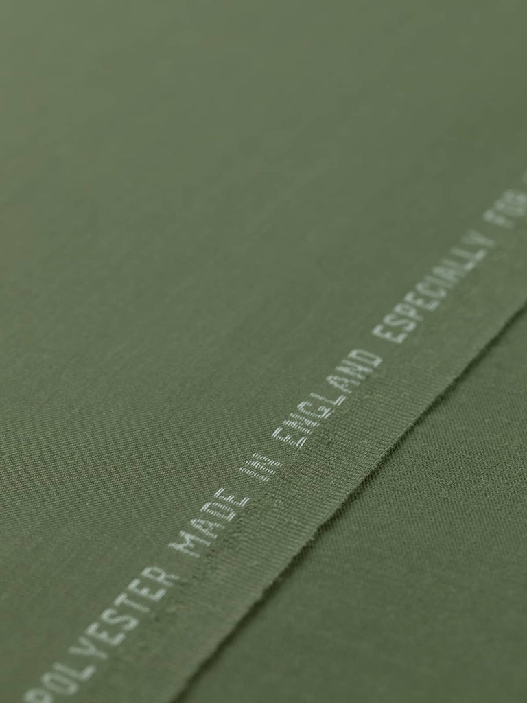 Flat, angled view of Desert Sand fabric laid out to showcase the even, fine twill weave and silky texture. The warm sand beige color, with faint grey undertones, makes it ideal for tailored garments or smart accessories with a minimalist, military-inspired edge.