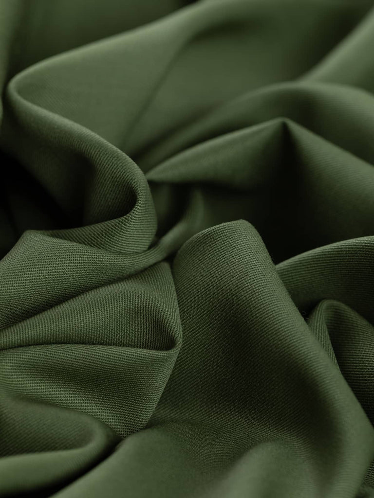 Angled twist shot of the Desert Sand wool-blend fabric, highlighting its fluid drape and tightly woven twill texture. The warm, neutral beige hue catches the light softly, evoking a clean, smart aesthetic with versatile styling potential.