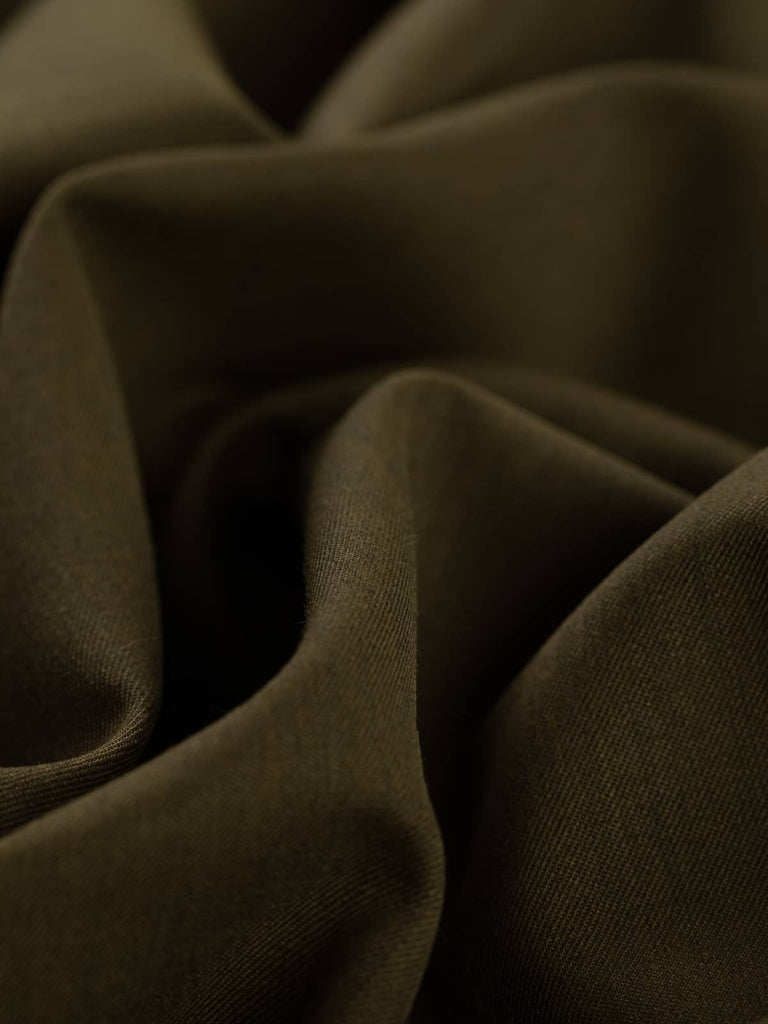 Angled twist shot of Dark Olive fabric, emphasizing its smooth, even texture and classic fine gabardine weave. The deep olive shade evokes a natural, grounded aesthetic, perfect for structured garments and fashion-forward street styles.