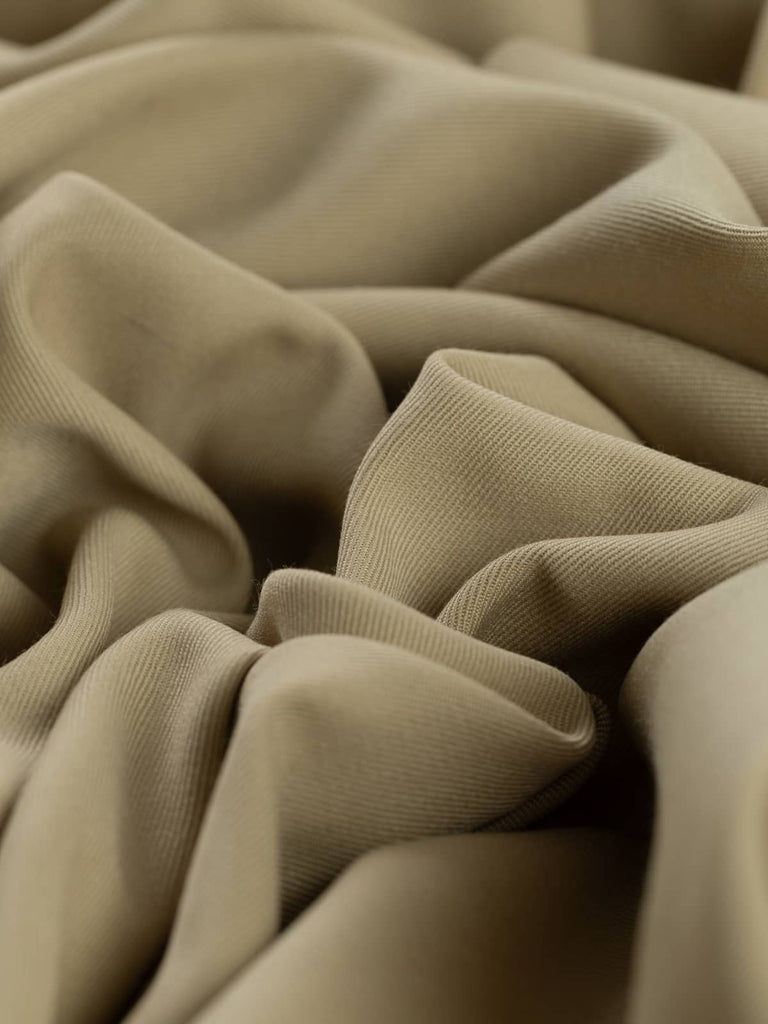 Angled twist shot of Buff Beige fabric, emphasizing its fine twill weave and natural, golden beige color. The soft texture and versatile tone make it perfect for creating tailored garments or adding an elegant, earthy touch to any wardrobe.