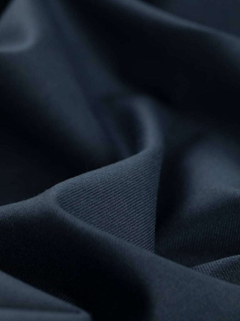 Angled twist shot of Old School Blue fabric, highlighting its close twill gabardine weave and soft, structured drape. The grey-blue tone shifts with the light, revealing a vintage Air Force blue influence and showcasing the fabric’s smart, resilient character.