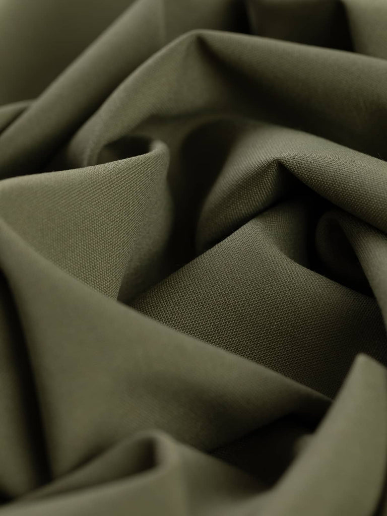 Angled twist shot of Dusted Olive fabric, highlighting its fluid drape, soft wool-poly blend, and subtle, natural olive-beige hue.