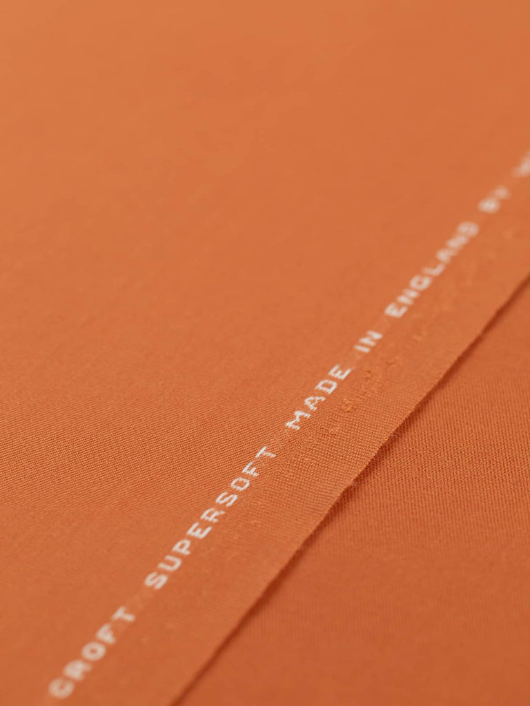 Flat, angled view of Rusty Orange fabric, capturing its deep rust-orange colour, lustrous finish, and crisp twill texture. Ideal for smart, structured pieces or bold accessories.