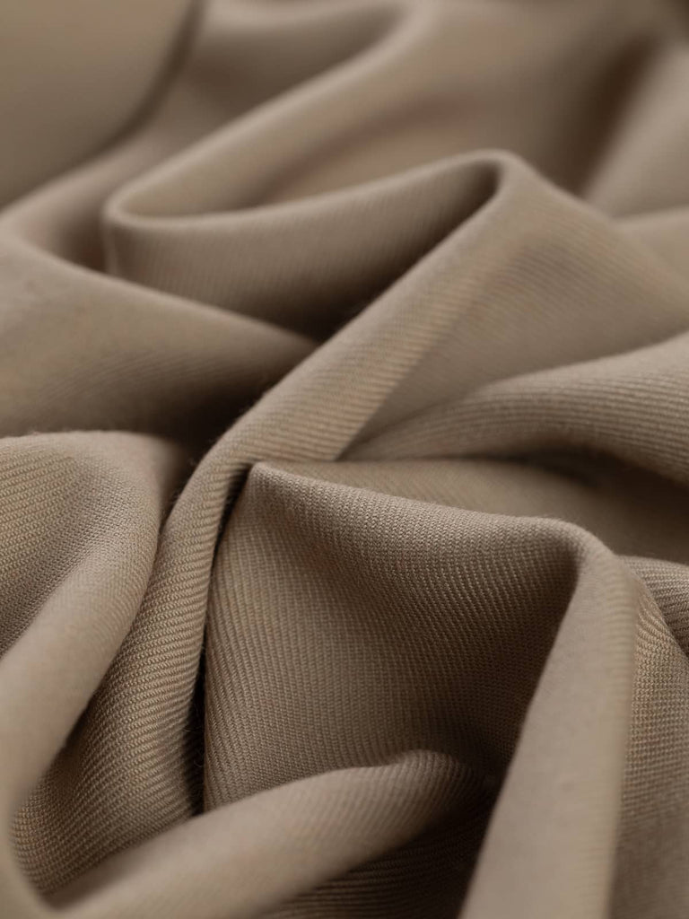 Angled twist shot of Mocha Beige fabric, highlighting its smooth wool-poly blend, fluid drape, and warm neutral tone. Perfect for chic, understated wardrobe staples.