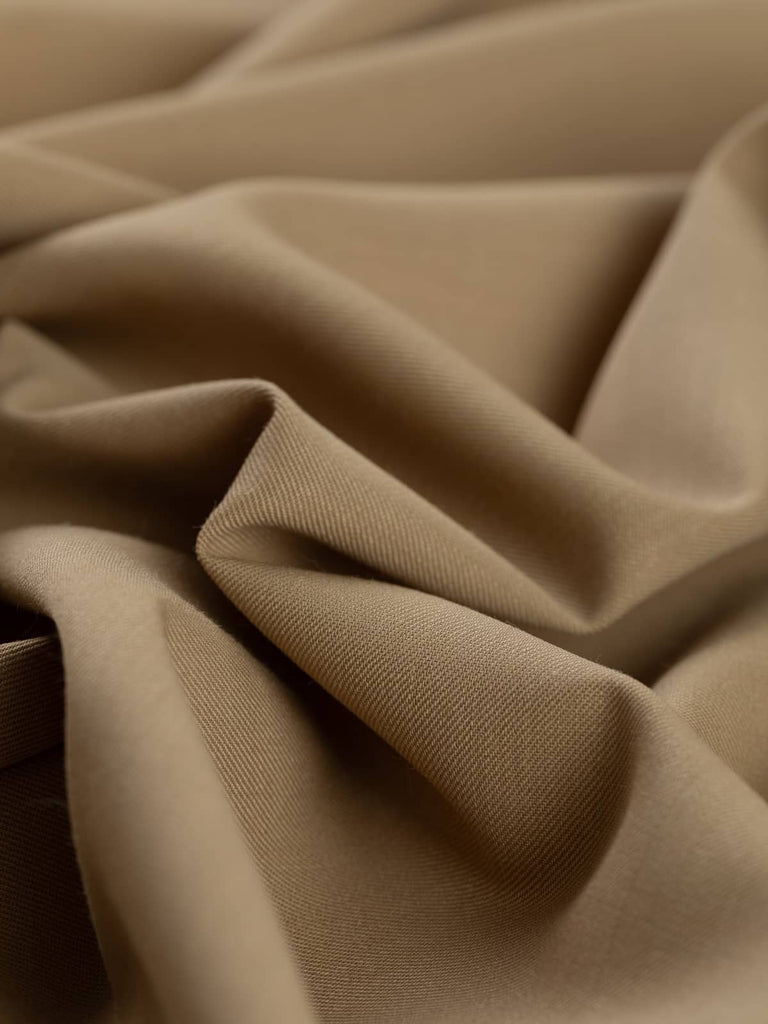 Angled twist shot of Priory Parchment fabric, highlighting its soft drape, smooth wool texture, and warm, natural tone