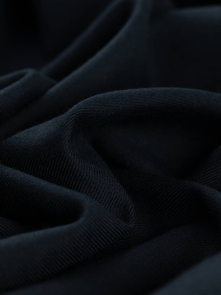Close-up angled twist of Seriously Navy wool-blend serge, highlighting its deep navy hue, lightly brushed fine wool texture, and distinctive twill diagonal lines. The fabric shows durability with an elegant, structured drape.