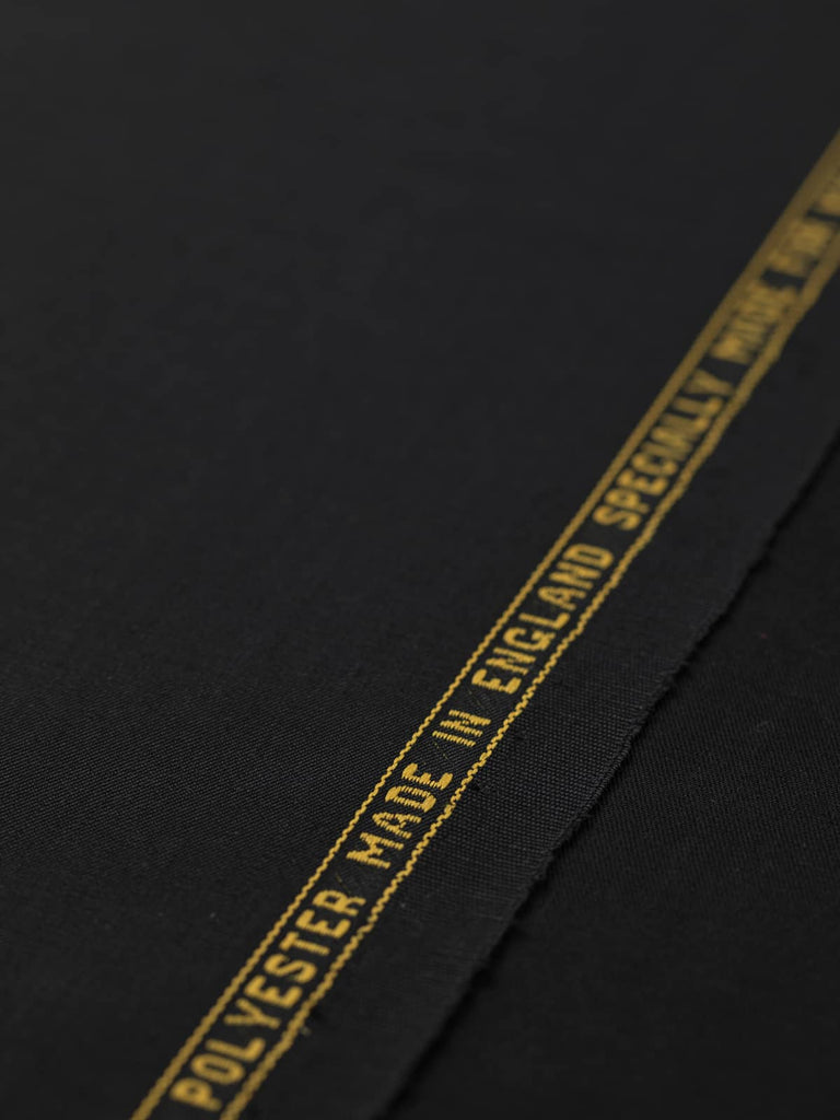 Flat angled view of Black Obsidian wool-blend, highlighting its deep black tone, classic twill structure, and even, smooth surface texture.