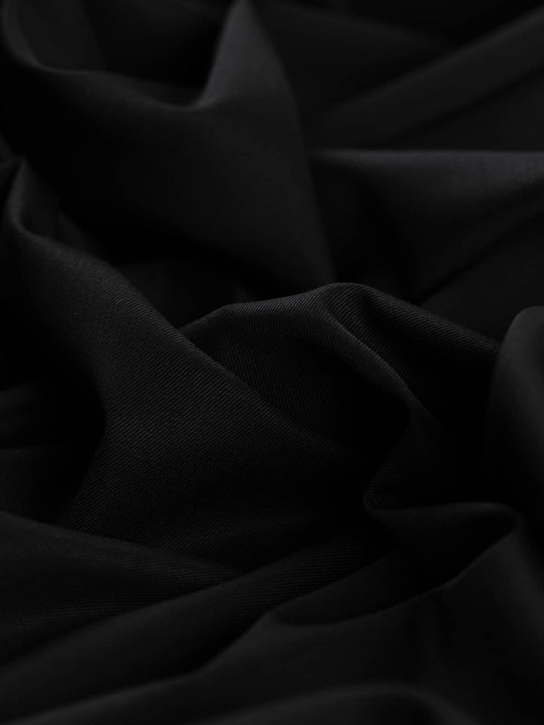 Close-up twist of Black Obsidian wool-blend fabric, showing its rich solid black hue, fine twill weave, and soft structured drape with subtle sheen.