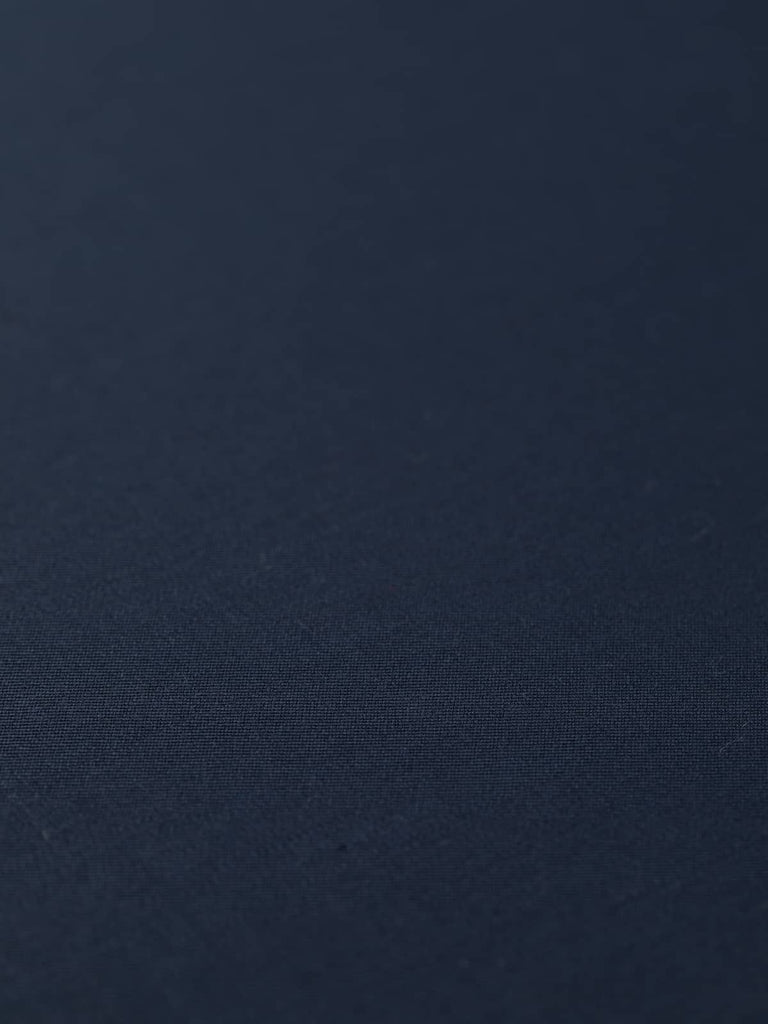 Flat angled view of Oxford Noir wool-blend twill fabric, highlighting its deep navy hue with black undertones, fine smooth surface, and elegant, weighty drape.