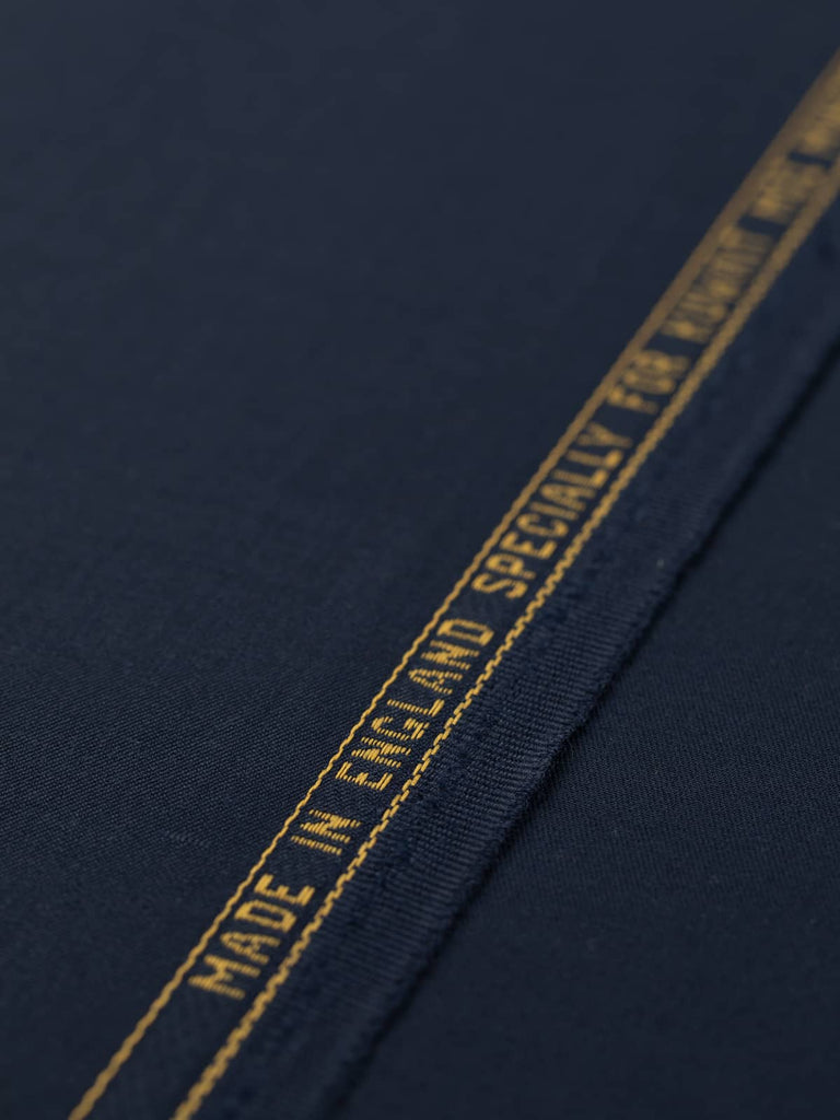 Flat angled view of Oxford Noir wool-blend twill fabric, highlighting its deep navy hue with black undertones, fine smooth surface, and elegant, weighty drape.