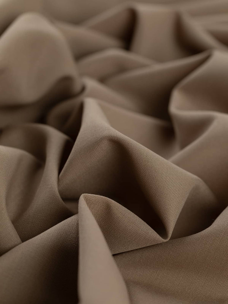 Close-up twist of Mocha Mousse wool-blend worsted fabric, showing even fine twill weave, soft drape, and warm neutral beige-taupe tone perfect for tailored garments.