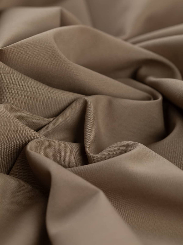Close-up twist of Mocha Mousse wool-blend worsted fabric, showing even fine twill weave, soft drape, and warm neutral beige-taupe tone perfect for tailored garments.