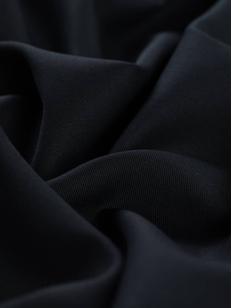 Close-up twist of Urban Midnight wool-blend stretch fabric, showing smooth twill texture, soft drape, and subtle elastane-enhanced flexibility.