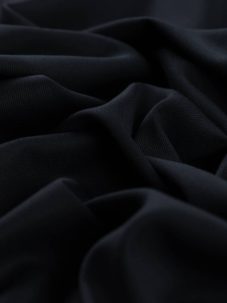 Close-up twist of Urban Midnight wool-blend stretch fabric, showing smooth twill texture, soft drape, and subtle elastane-enhanced flexibility.