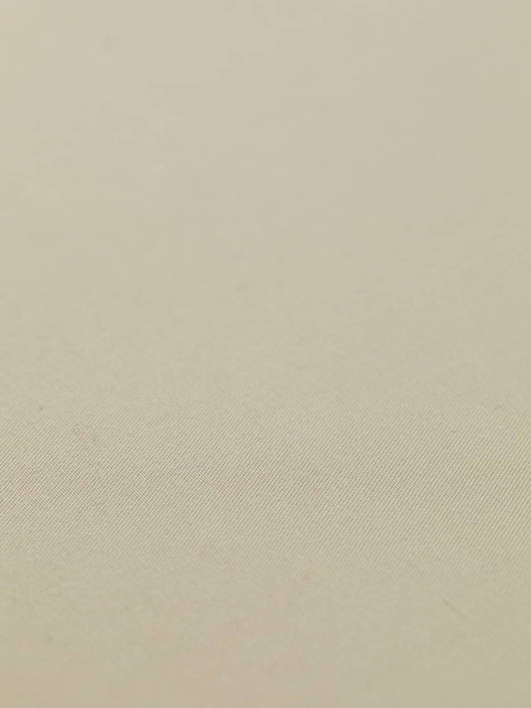 Flat angled view of Chino Beige wool-blend gabardine fabric, highlighting its light sandy beige color, crisp fine twill texture, and elegant weighty drape suitable for structured or fluid silhouettes