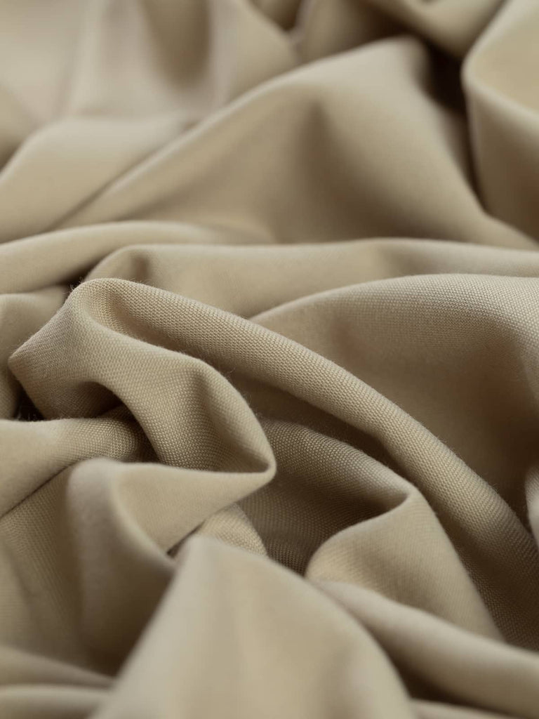Close-up twist of Chino Beige wool-blend gabardine, showing even fine twill weave, soft brushed texture, and versatile light sandy beige tone ideal for tailored garments