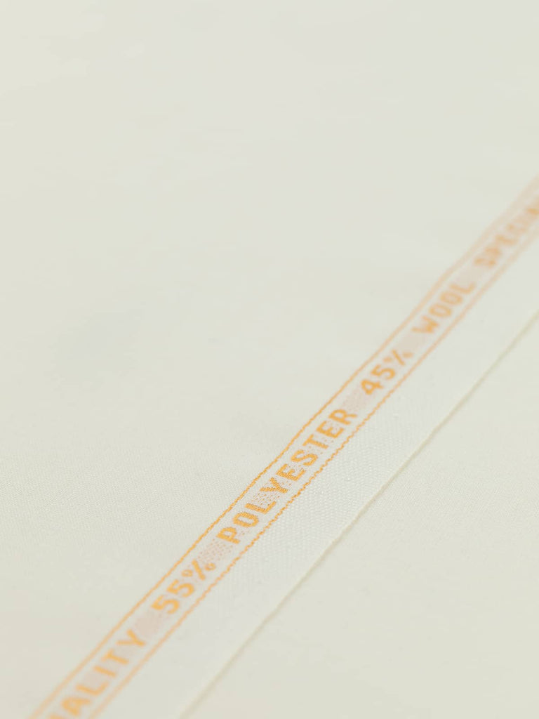 Flat angled view of Classic Ecru wool-blend worsted fabric, highlighting its pale cream-white tone, golden selvedge, and crisp yet elegant drape