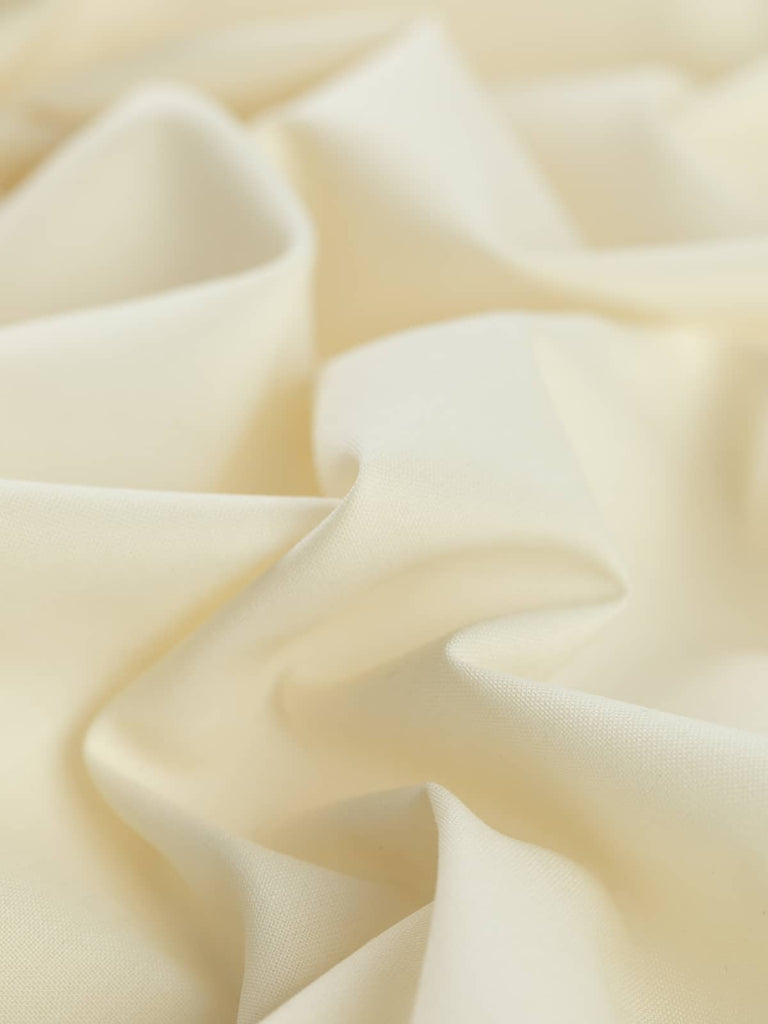 Close-up twist of Classic Ecru wool-blend fabric, showing soft, fine worsted texture, subtle sheen, and lightweight, fluid drape.