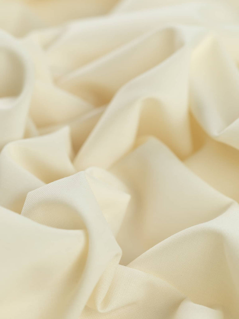 Close-up twist of Classic Ecru wool-blend fabric, showing soft, fine worsted texture, subtle sheen, and lightweight, fluid drape.