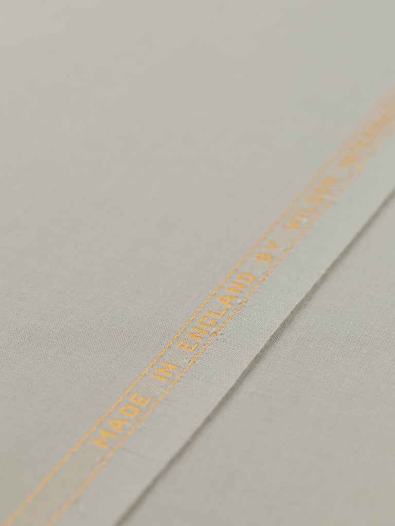 Flat angled view of Chino Beige wool-blend gabardine fabric, highlighting its light sandy beige color, crisp fine twill texture, and elegant weighty drape suitable for structured or fluid silhouettes.