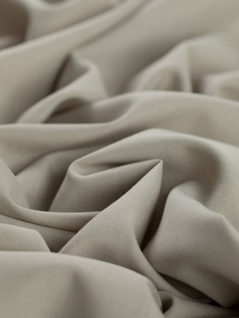 Close-up twist of Chino Beige wool-blend gabardine, showing even fine twill weave, soft brushed texture, and versatile light sandy beige tone ideal for tailored garments.