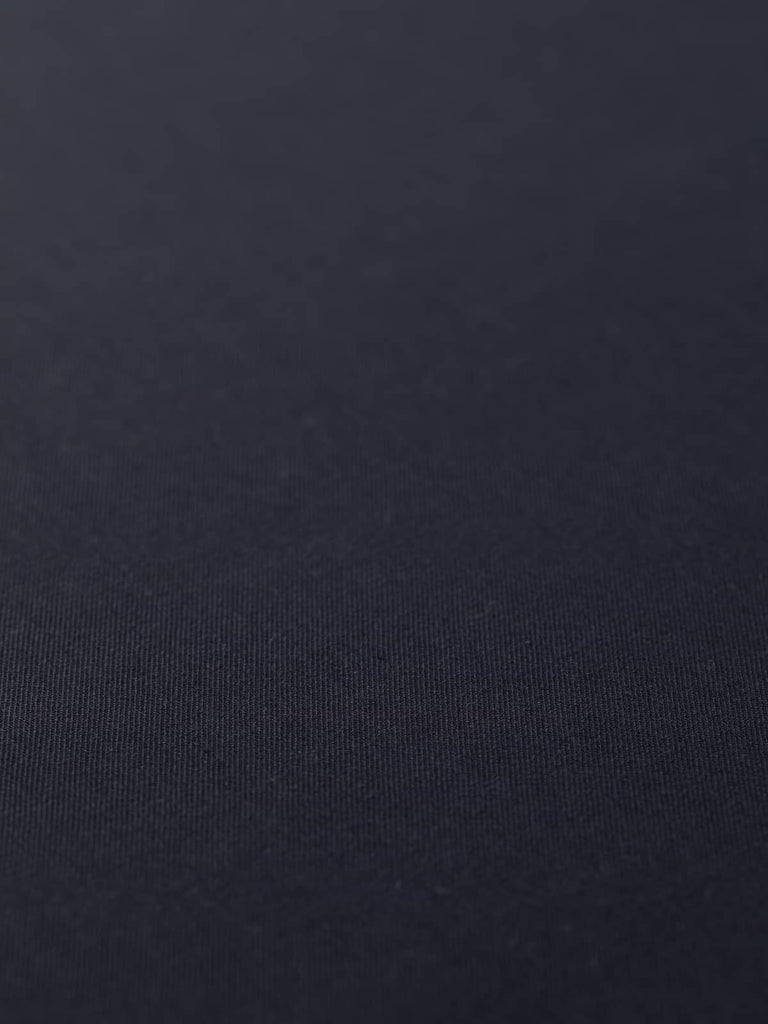 Flat angled view of Inkstone Navy wool-blend gabardine fabric, highlighting its deep dark navy shade, crisp fine twill texture, and elegant weighty drape ideal for tailoring.