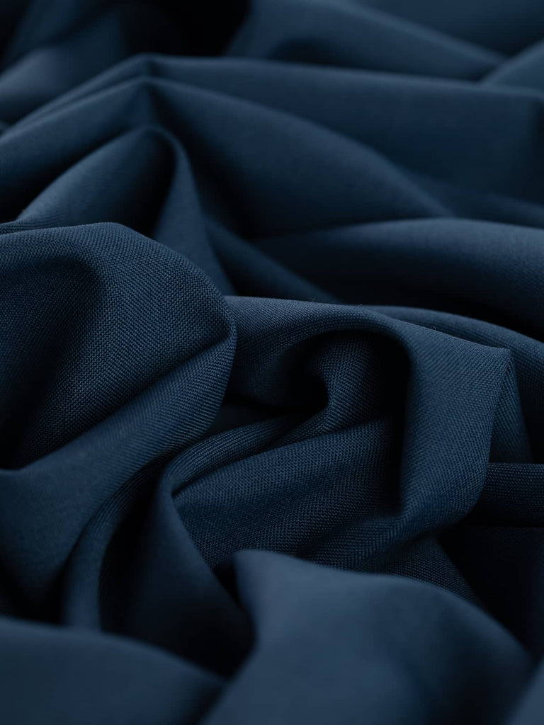 Twist of Midnight Maritime wool-blend worsted, showing soft swishy handle, refined flat weave, and rich oceanic navy tone with subtle twilight depth.