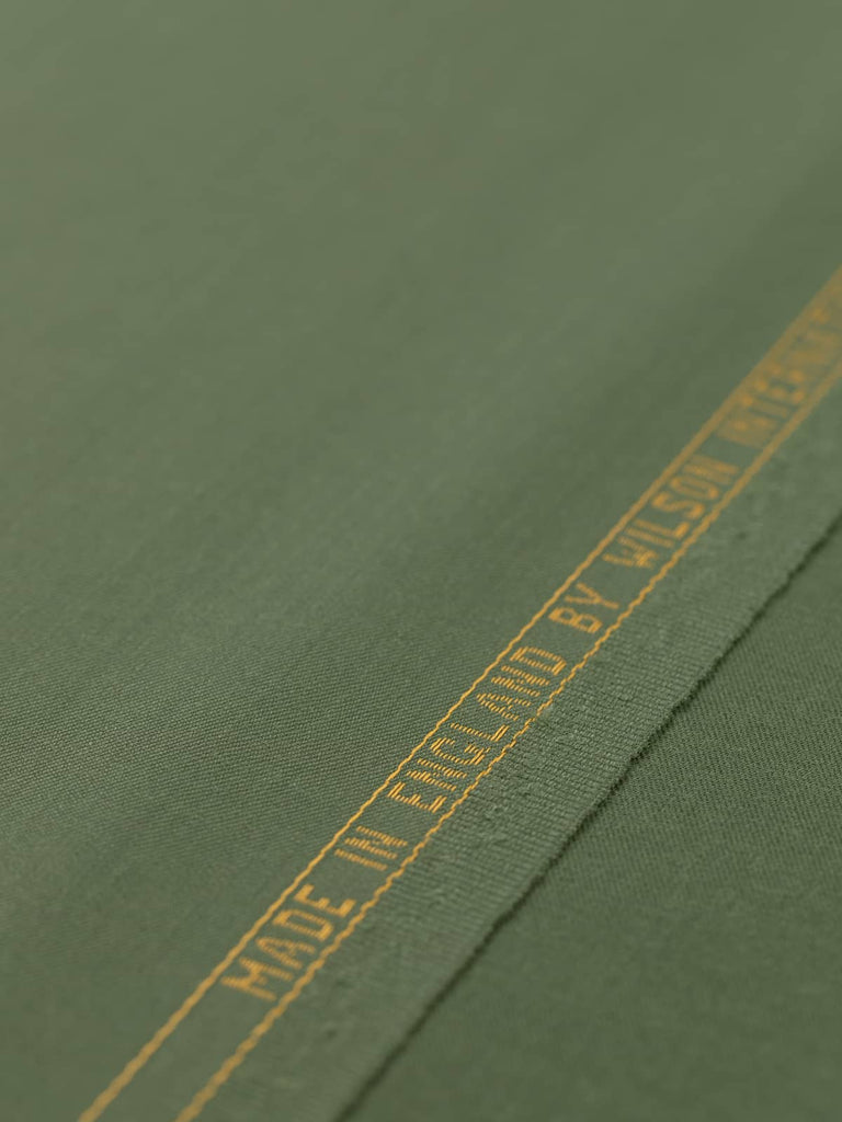 Flat angled view of Guardsman’s Green wool-blend twill fabric, highlighting its deep olive green colour, fine close twill weave, and versatile lightweight structure