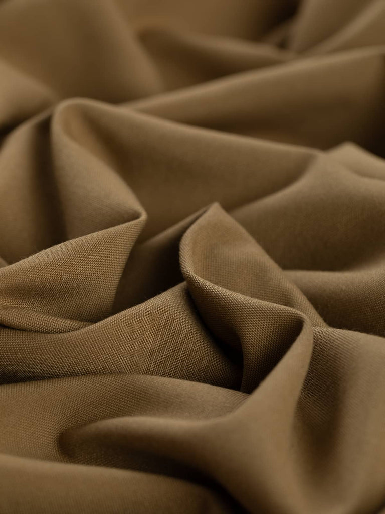 Twist of Golden Hazel wool-blend worsted fabric, showing soft cotton-like texture, smooth drape, and warm autumnal brown shade