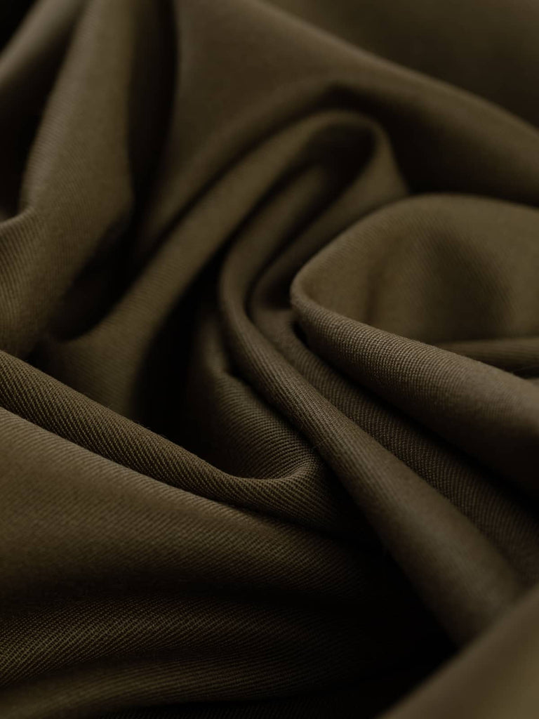 Twist of Earth Olive wool suiting fabric, highlighting fluid drape, soft brushed surface, and organic olive-brown hue with golden undertones