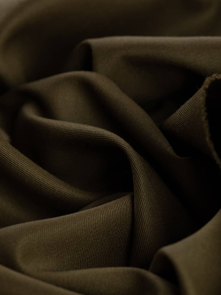 Twist of Earth Olive wool suiting fabric, highlighting fluid drape, soft brushed surface, and organic olive-brown hue with golden undertones