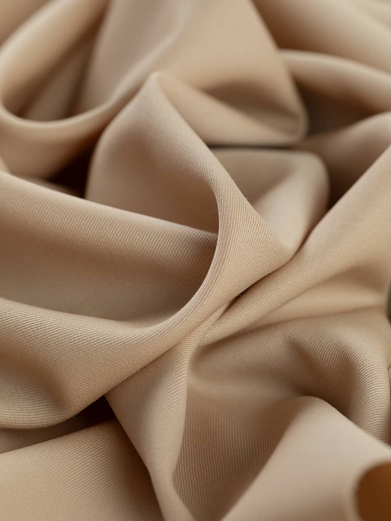 Twist of Blushed Oat 100% wool suiting fabric, showing smooth drape, soft brushed texture, and muted almond hue