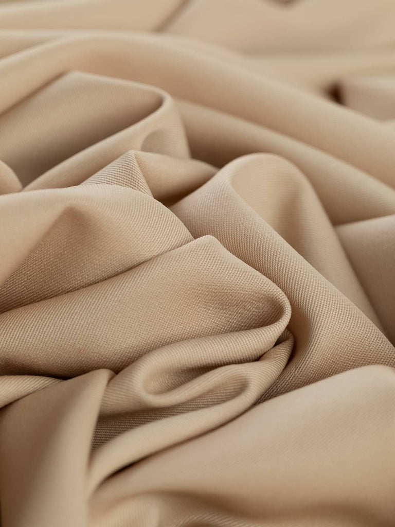 Twist of Blushed Oat 100% wool suiting fabric, showing smooth drape, soft brushed texture, and muted almond hue