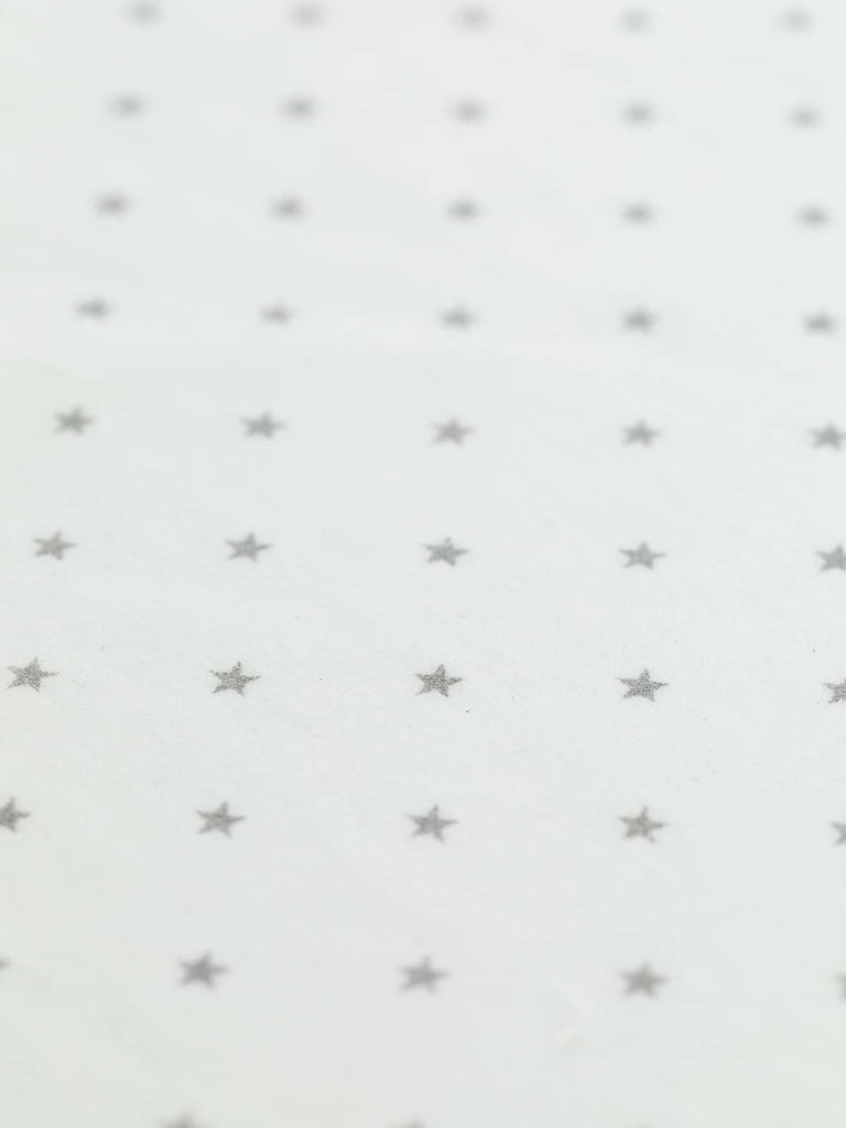 A close-up of Snow & Stars Cotton Velvet, showcasing its smooth, velvety surface with a short directional pile. The delicate silver-grey star print adds a whimsical touch, perfect for capes, dresses, and craft projects.