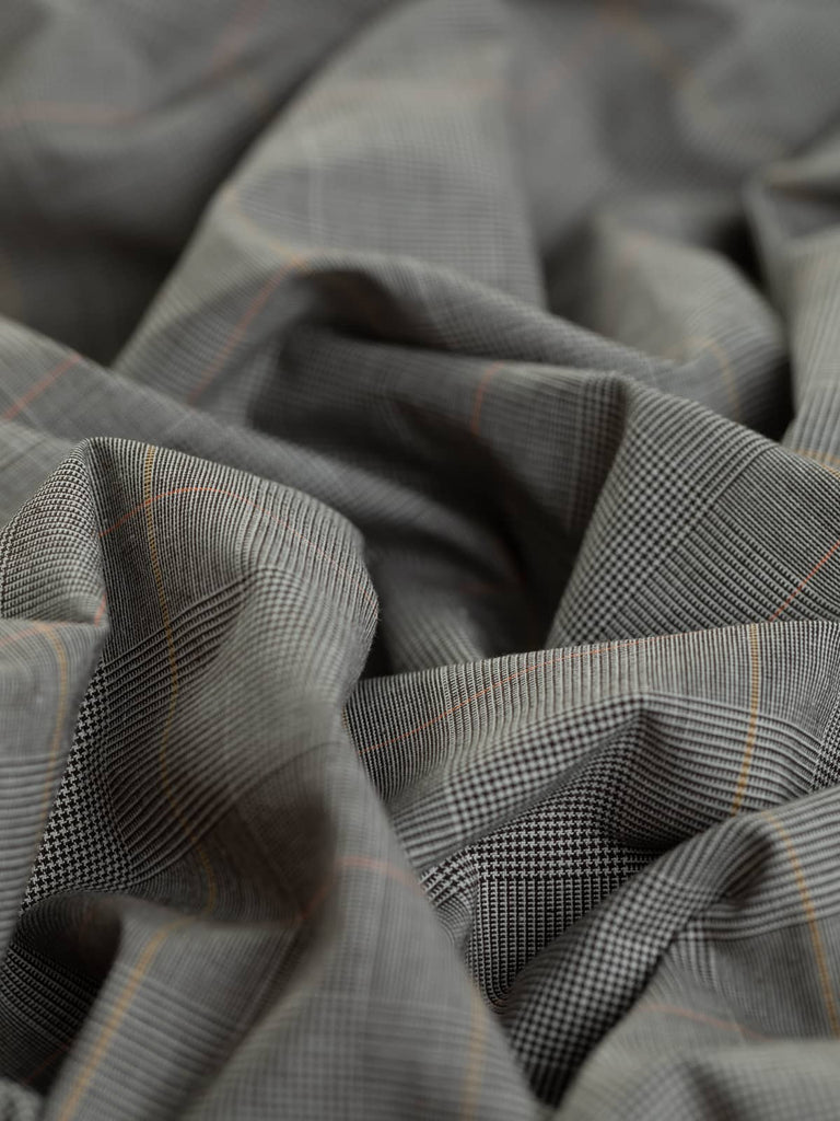 Morning Espresso District Check features a classic Princely checked weave in dark espresso brown and natural white with pops of yellow and orange, offering a stylish British design with Italian flair. This mediumweight stretch cotton suiting fabric is ideal for blazers, trench coats, and versatile separates.