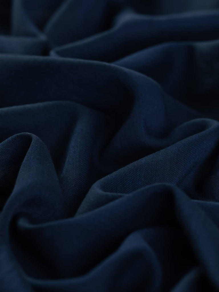 Night Whisper Navy is a lightweight viscose challis fabric in a classic navy hue, offering a soft, slightly translucent drape with a fine twill weave. Ideal for creating flowing blouses, dresses, and skirts with elegant ruffles, tiers, and draped details.