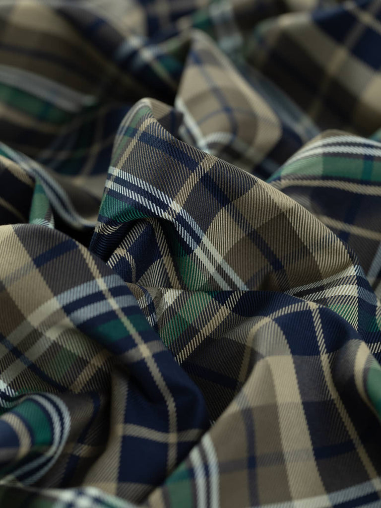 City Watch Plaid is a mediumweight cotton gaberdine twill fabric featuring a classic British designer-style plaid in midnight navy, olive green, sandstone, forest green, and white. Ideal for creating hardwearing outerwear, trench coats, pleated skirts, and utility-style garments with a stable handle and silky feel.