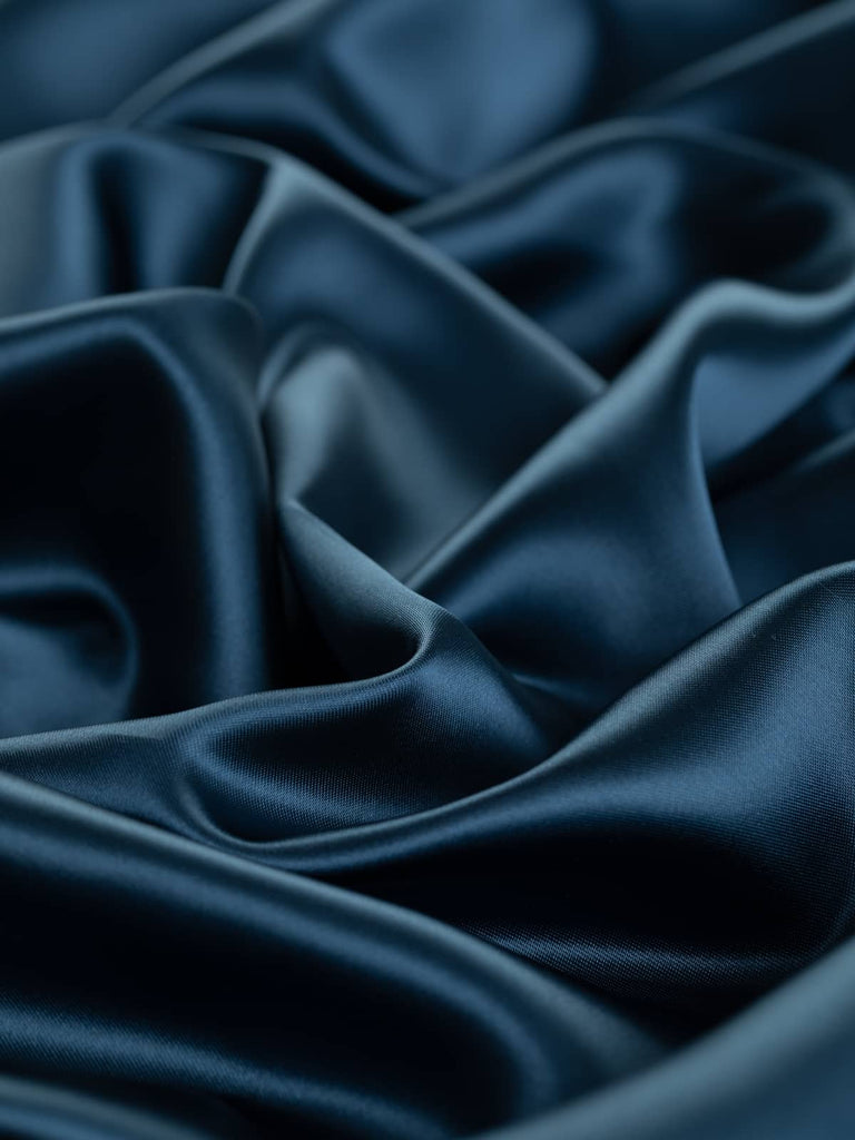 Luxurious rich metallic blue lining fabric, 144cm wide, featuring subtle steel grey undertones and a fine satin weave. Made from a blend of viscose and acetate, this light but strong fabric is exceptionally soft, silky, and smooth, offering a lustrous finish with a cool drapey feel, perfect for lining jackets, dresses, and high-end occasion wear.