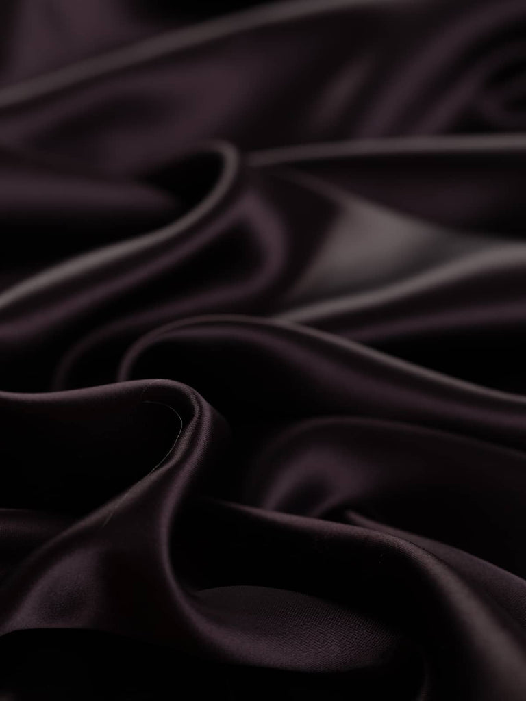 Dark brown purple plum lining fabric, 144cm wide, with a rich hue reminiscent of sweet Damson Jam, crafted from a blend of viscose and acetate in a solid fine satin weave. This light yet strong fabric is incredibly soft and silky, with a smooth, lustrous finish and a cool, drapey feel, perfect for lining jackets, skirts, and dresses.