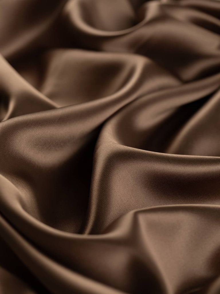 Soft warm brown satin lining fabric, 144cm wide, with a glossy finish reminiscent of sweet caramel sauce. This light yet strong viscose and acetate blend offers a silky, smooth texture with a lustrous, drapey feel, perfect for lining jackets, skirts, and dresses, and also suitable as a high-quality satin outer fabric.