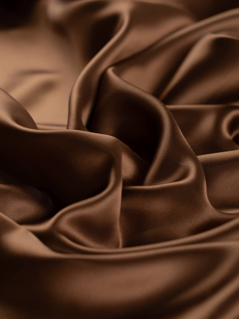Rich burnished brown satin lining fabric, 144cm wide, featuring warm rust undertones reminiscent of a gleaming chestnut. This light yet strong viscose and acetate blend offers a soft, silky, and smooth texture with a lustrous, drapey feel, perfect for lining jackets, skirts, and dresses, and suitable as a high-quality satin outer fabric.
