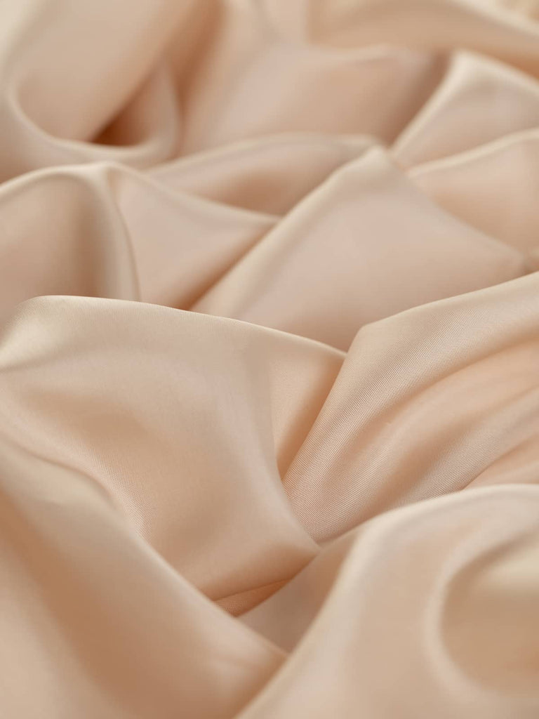 Soft pearl-like beige lining fabric, 140cm wide, in a superfine solid flat weave. This very light 100% viscose fabric offers a silky, smooth texture with a subtle semi-shiny finish, perfect for lining jackets, skirts, and dresses, providing a cool and drapey feel ideal for elegant tailoring and fashion projects.