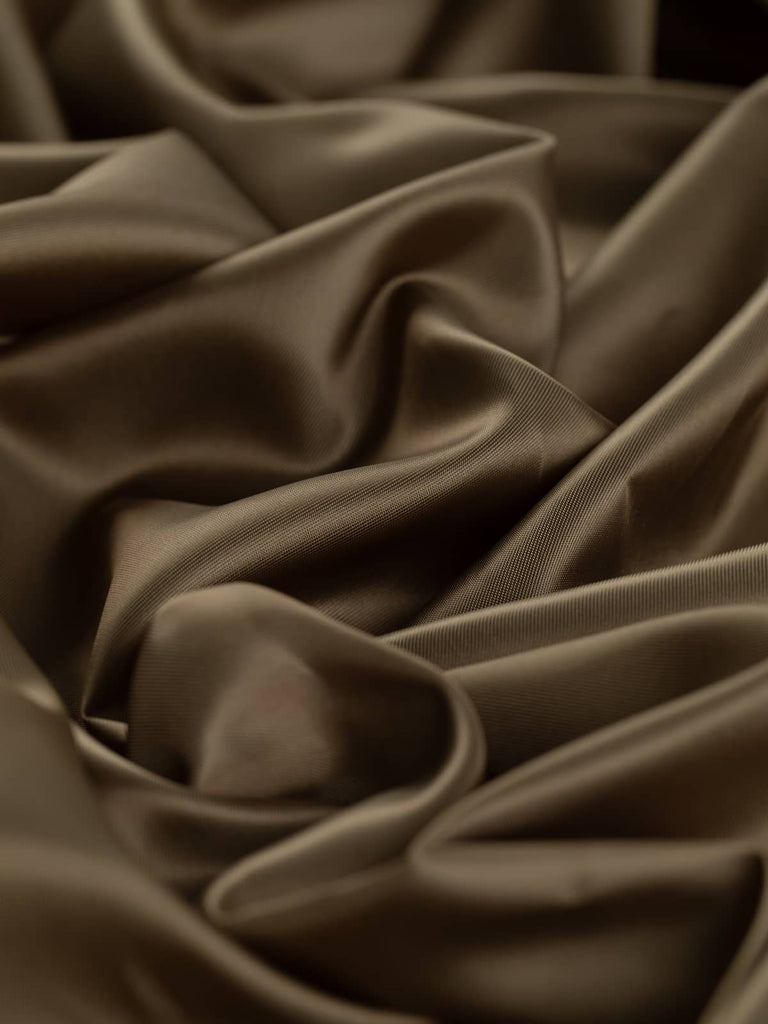 Golden-bronze brown lining fabric, 140cm wide, featuring a metallic semi-shine reminiscent of antique bronze sculptures. This light fabric, composed of 80% viscose and 20% acetate in a superfine solid twill weave, offers a silky, smooth, and lustrous texture with a drapey, cool feel, ideal for lining jackets, skirts, and dresses in classic tailoring and fashionable occasion wear.