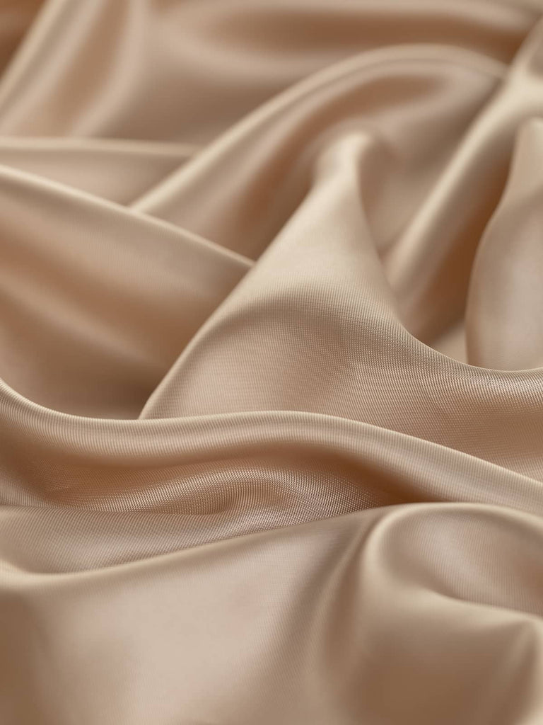 Warm beige twill lining fabric with peachy undertones, 140cm wide. This light fabric, made from 80% viscose and 20% acetate, features a superfine solid twill weave and a semi-shiny satin-like finish. Its soft, silky, and smooth texture, along with its drapey and cool feel, makes it ideal for lining jackets, skirts, dresses, and bags, adding a touch of sophistication to corporate and occasion wear.