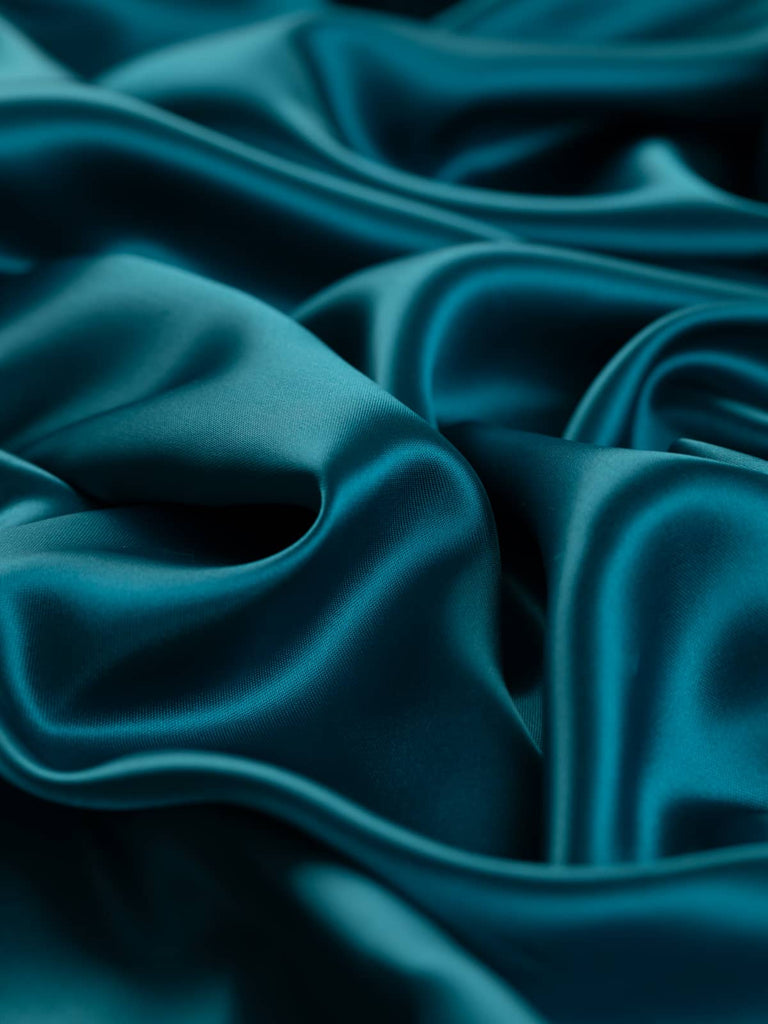 Rich teal tourmaline-inspired lining fabric with a lustrous satin finish, 144cm wide. This deep turquoise teal fabric, made from 100% acetate, is perfect for lining jackets, dresses, and skirts, offering a silky and drapey feel.