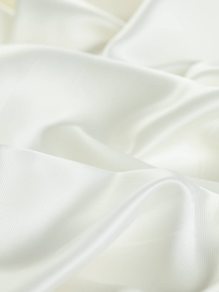 Detailed close-up of Silky Acetate & Viscose Twill Lining - Cream Pearl fabric with a distinctive shot twill weave pattern, ideal for jackets, waistcoats, skirts, and dresses.