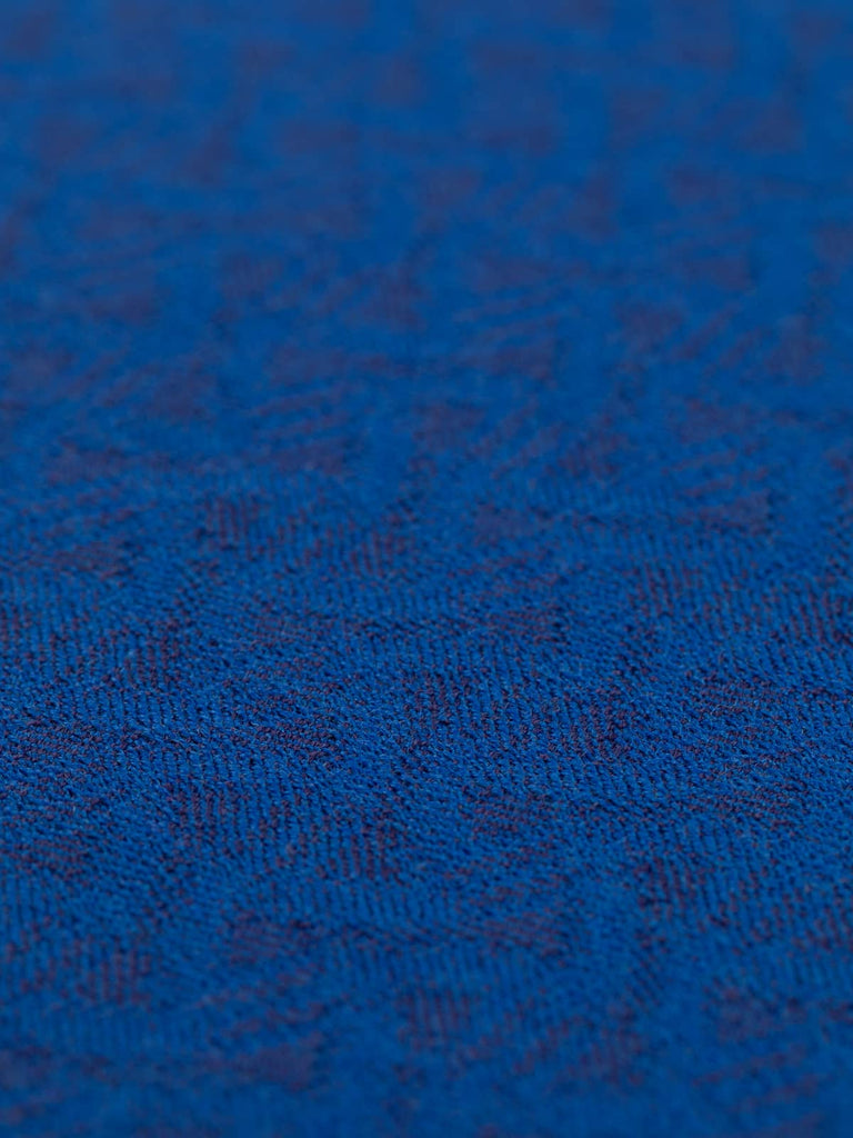 A flat, angled view of the Santorini Wave fabric, highlighting the rhythmic, wave-inspired pattern. The grainy surface texture and heritage-inspired colour palette convey a timeless, sophisticated style.